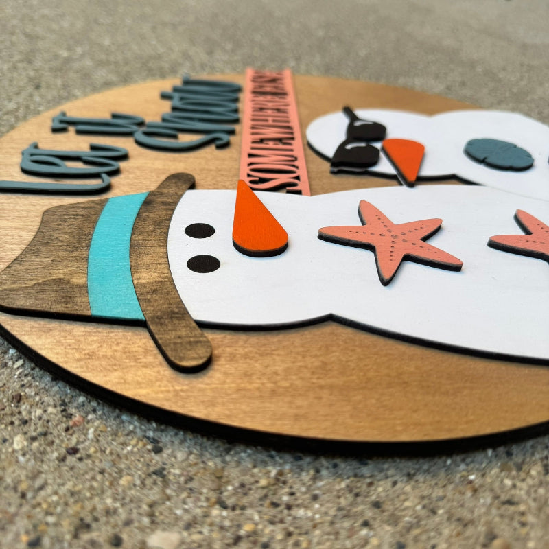 Wooden snowman decoration with starfish accents on a concrete surface