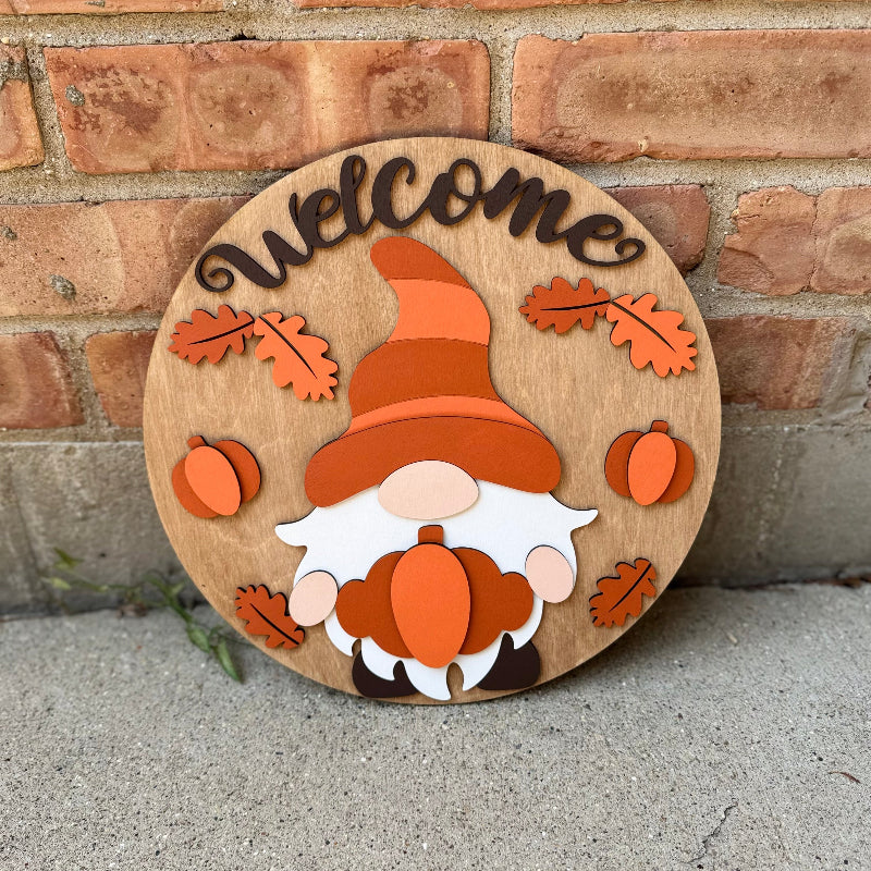 Wooden sign with a gnome design and 'welcome' text against a brick wall.