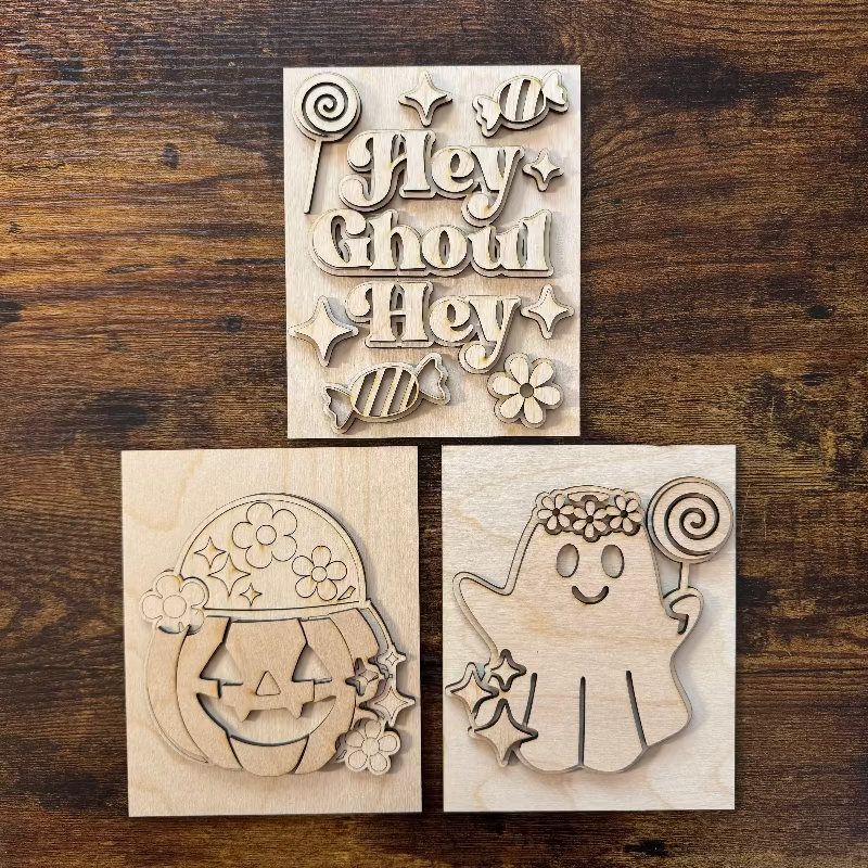 Three wooden Halloween sign DIY kits on a wooden surface