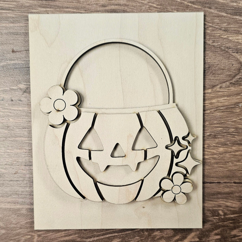 Wooden Halloween decoration with pumpkin face, flowers, and stars on a wooden surface