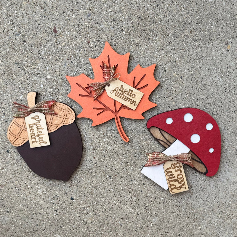 Autumn-themed decorations including an acorn, maple leaf, and mushroom on a concrete surface.