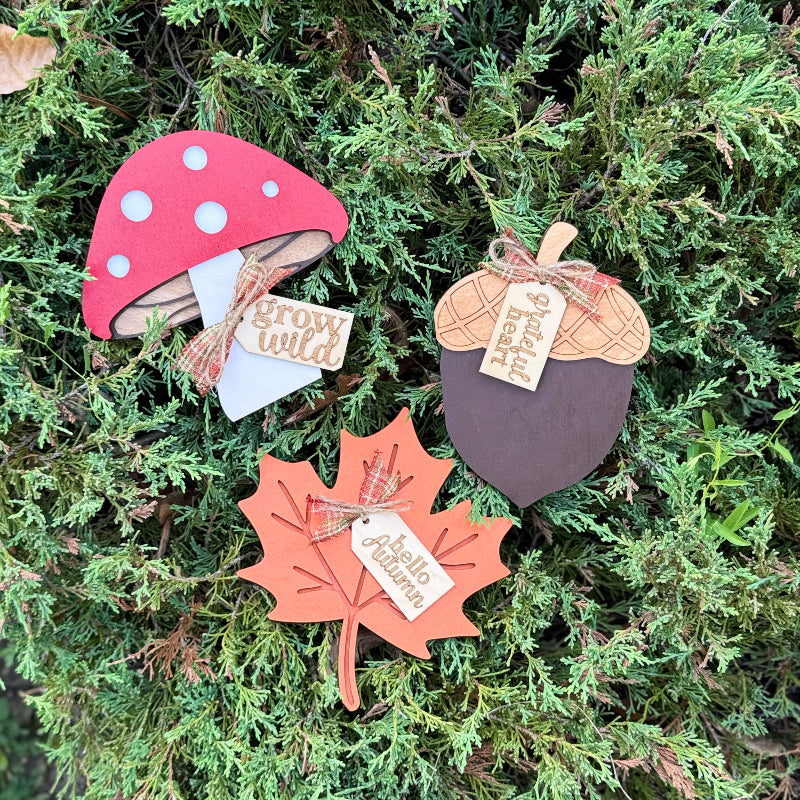 Decorative autumn-themed items including a mushroom, leaf, and acorn on a green leaf background.