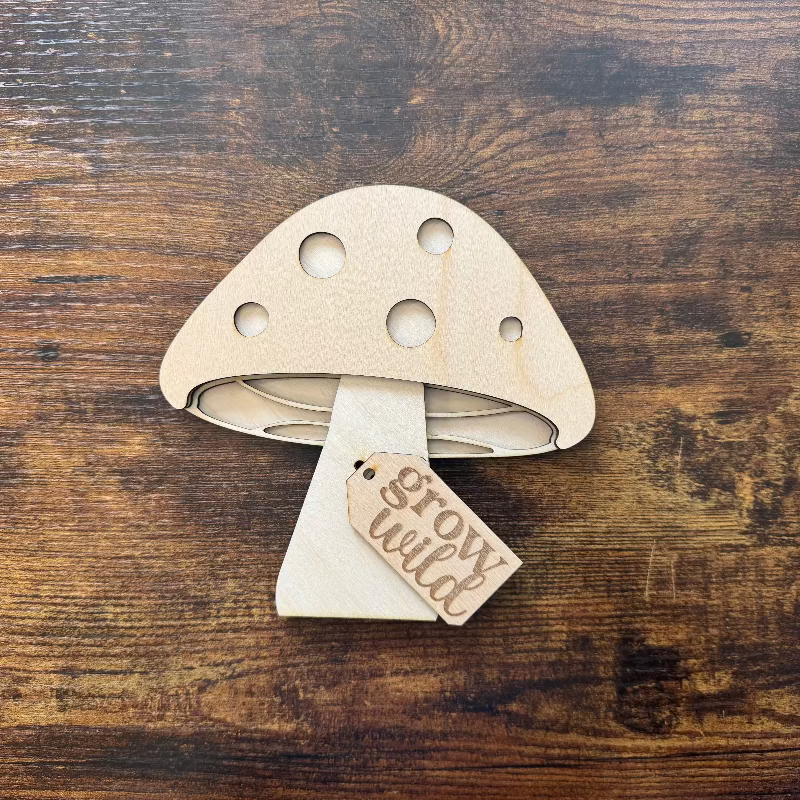 Wooden mushroom-shaped shelf sitter with a 'grow wild' tag on a wooden surface