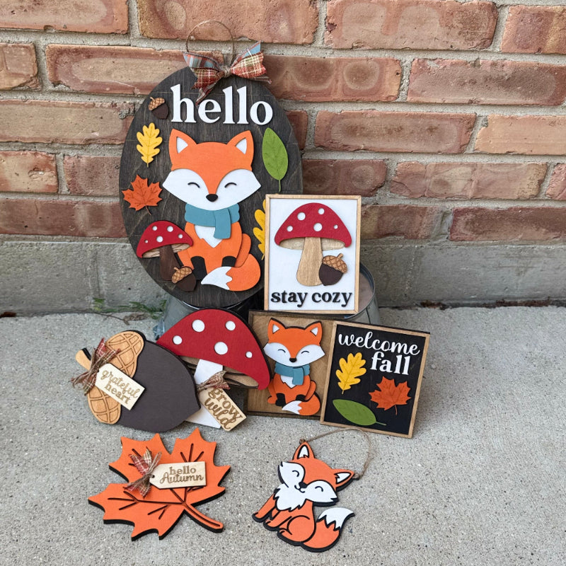 Set of autumn-themed decorative signs with foxes, leaves, and mushrooms against a brick wall.