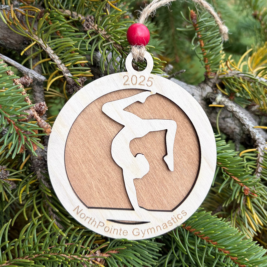 Wood ornament with a gymnast doing a handstand on a balance beam. Engraved with the gym's name for a fund raiser.