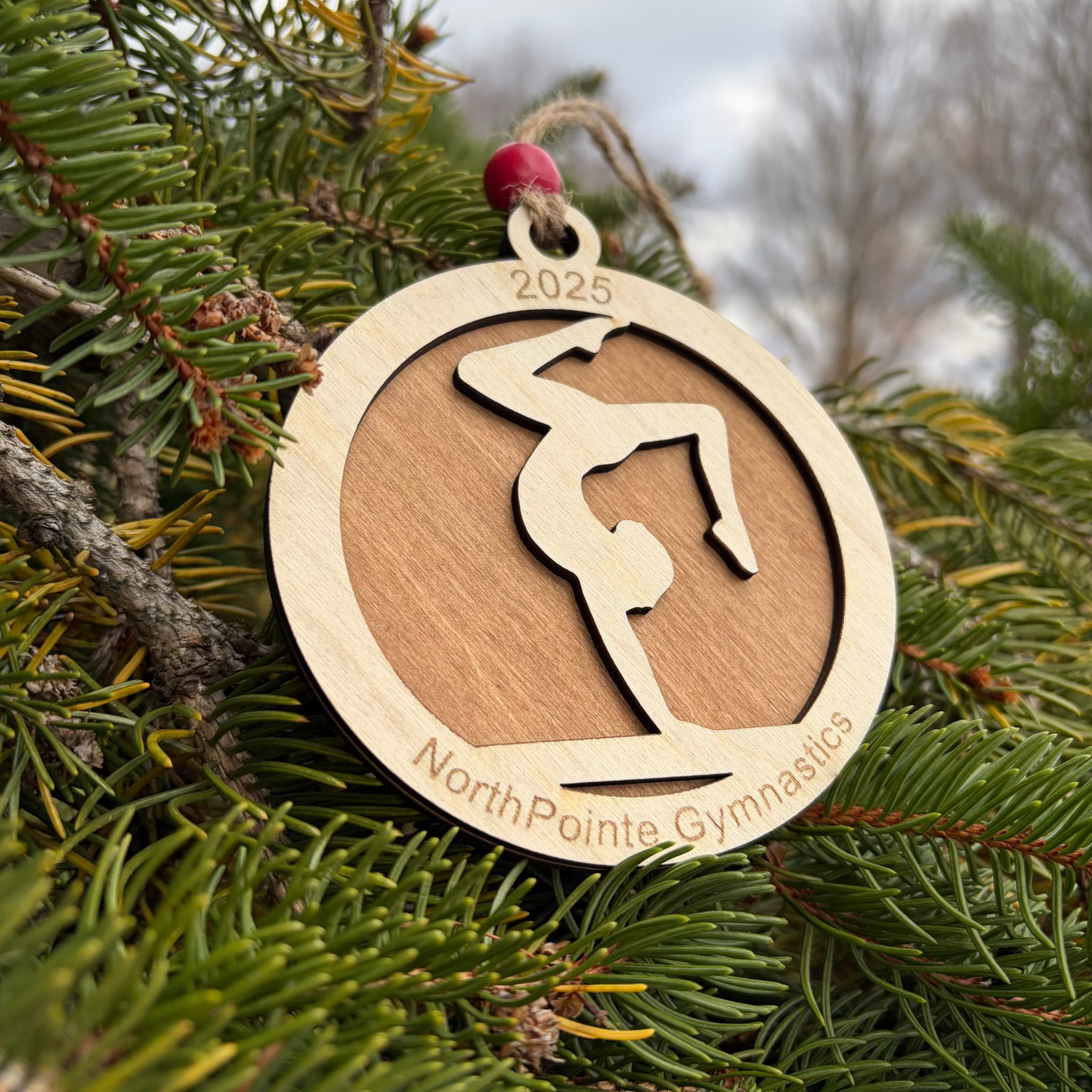 Wood ornament with a gymnast doing a handstand on a balance beam. Engraved with the gym's name for a fund raiser.