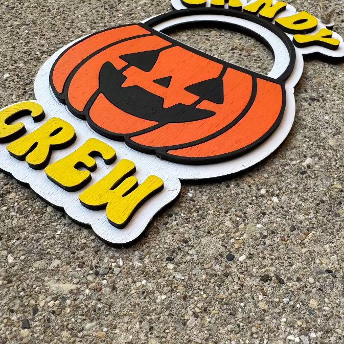 Halloween-themed sign with a pumpkin and 'Candy Crew' text on a concrete surface