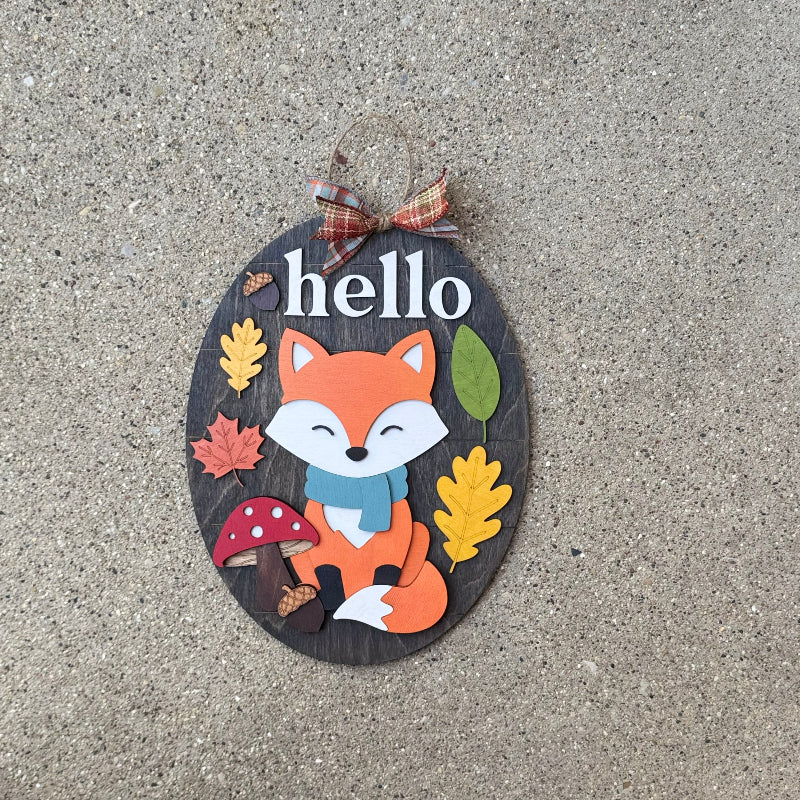 Decorative sign with a fox illustration and 'hello' text on a wood surface