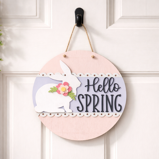 Decorative 3D wood sign with a bunny and flowers on a pink background, hanging on a white door.