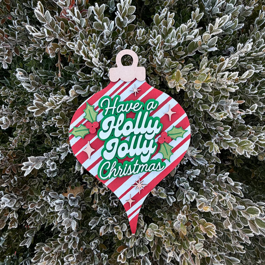 Decorative Christmas ornament sign with 'Holly Jolly Christmas' text on a frosty bush background