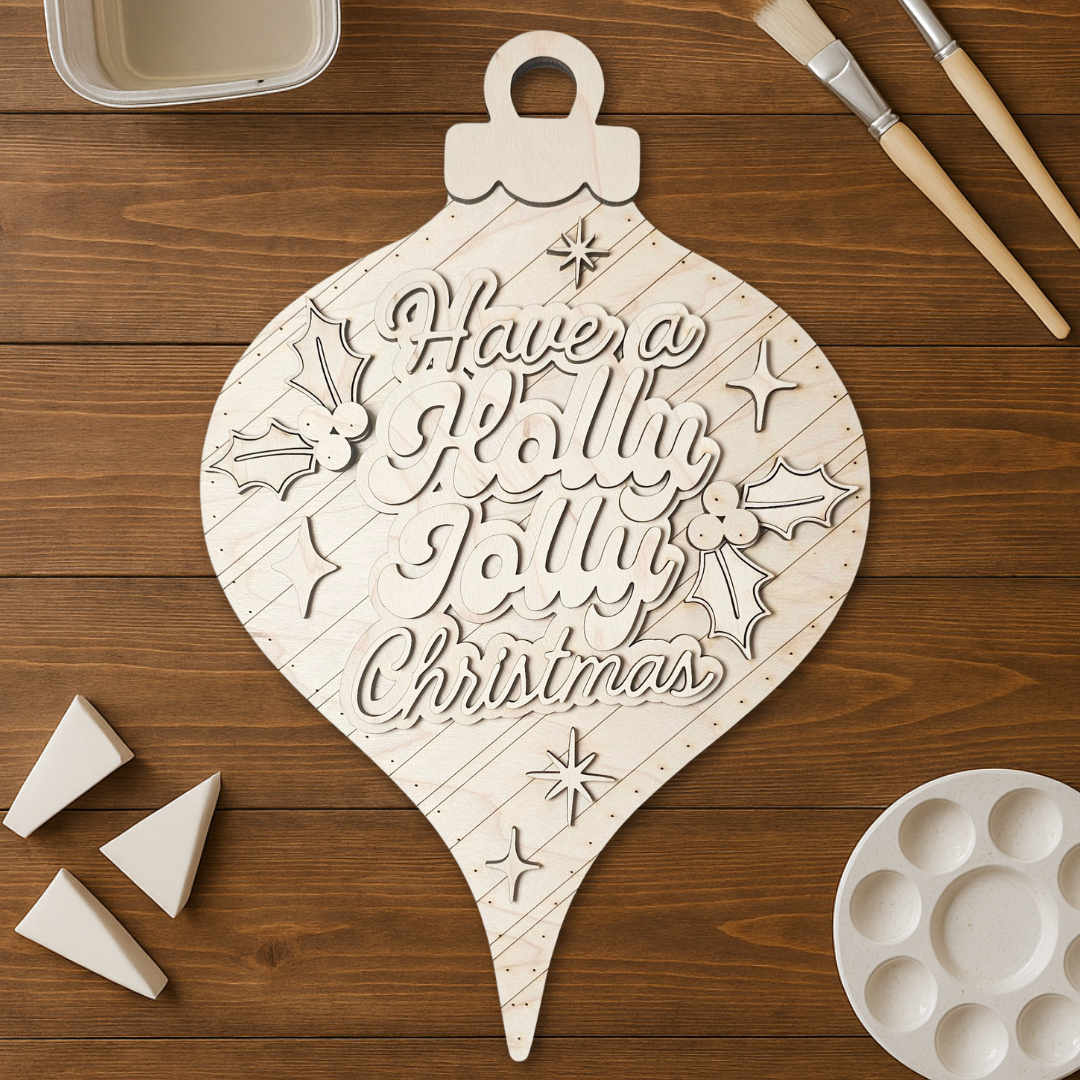 Wooden ornament with 'Have a jolly jolly Christmas' text on a wooden surface with painting tools.