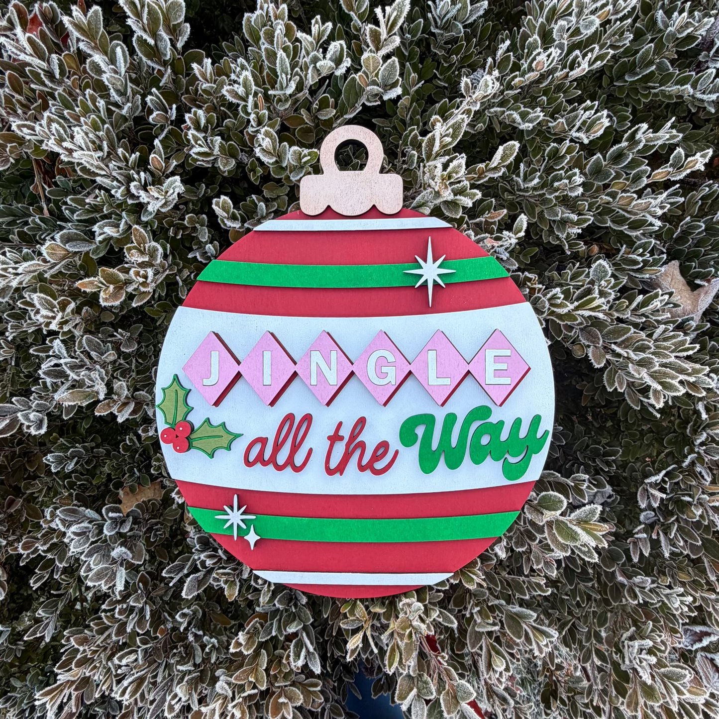 Decorative Christmas ornament sign with 'Jingle all the Way' text on a frosted tree background