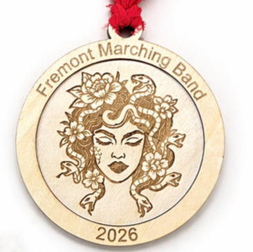 Wooden ornament with engraved design and text 'Fremont Marching Band 2026' on a white background