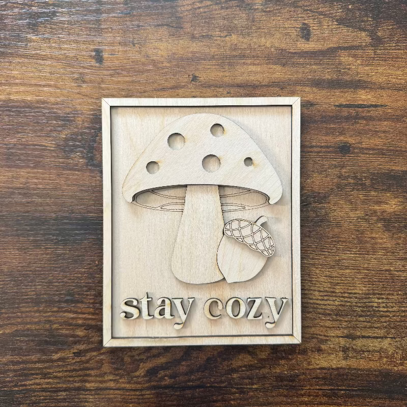 Wooden 3D kit with mushroom design and 'stay cozy' text on a wooden background