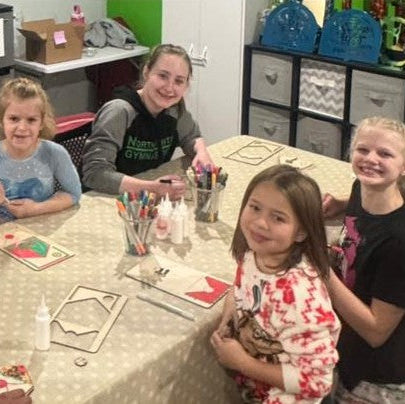 Children sitting around a table with art supplies in a classroom setting.