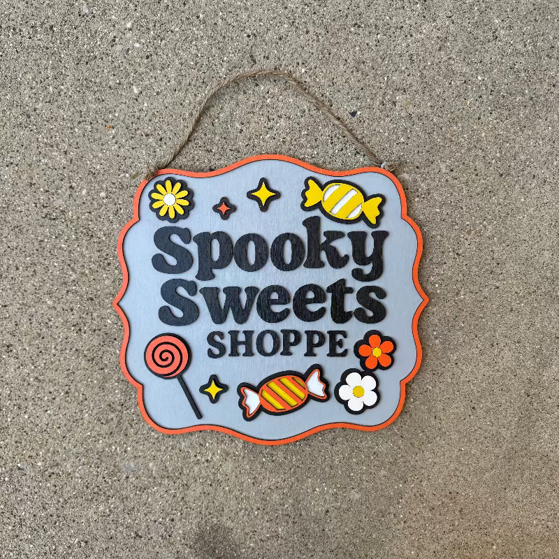 Decorative sign with 'Spooky Sweets Shoppe' text on a textured surface