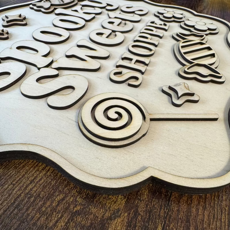 Wooden sign with decorative text and a lollipop design on a wooden surface