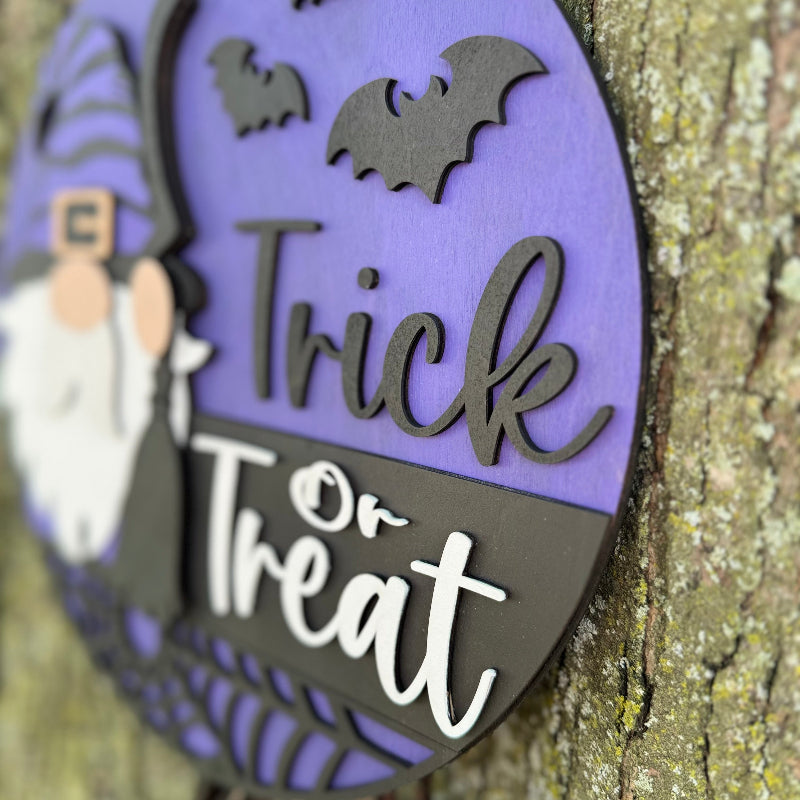 Halloween-themed decorative sign with a gnome, bats, and 'Trick or Treat' text on a purple background.