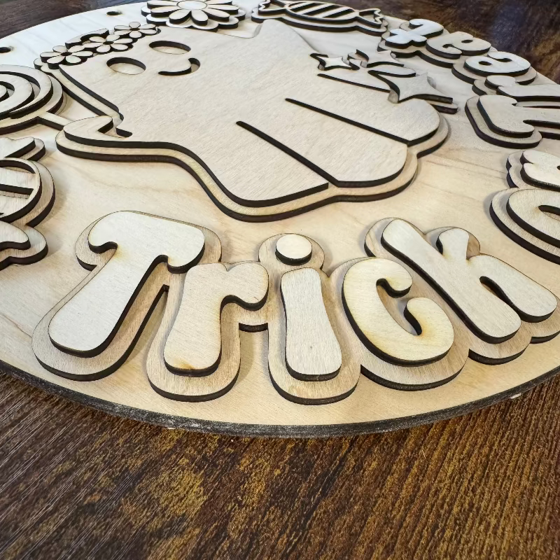 Round wooden sign with a ghost eating candy saying "Trick or Treat"