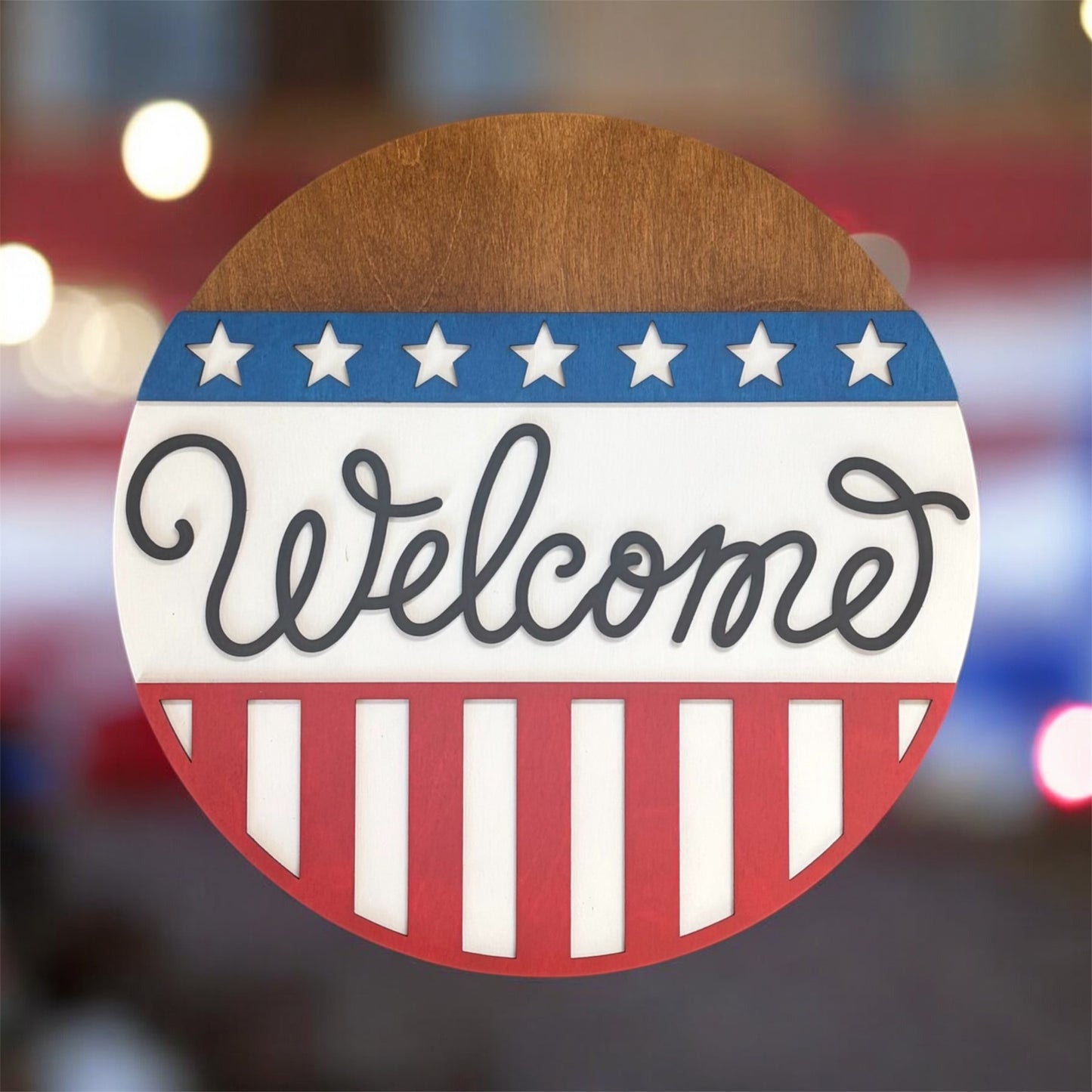 Round wooden sign with 'Welcome' text, stars, and stripes on a blurred background
