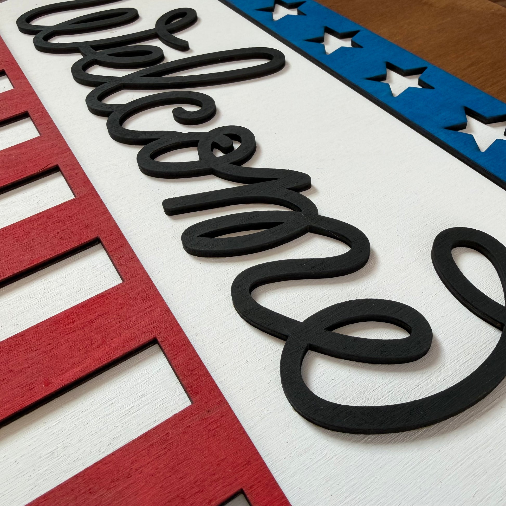 Decorative welcome sign with red, white, and blue colors and black text.