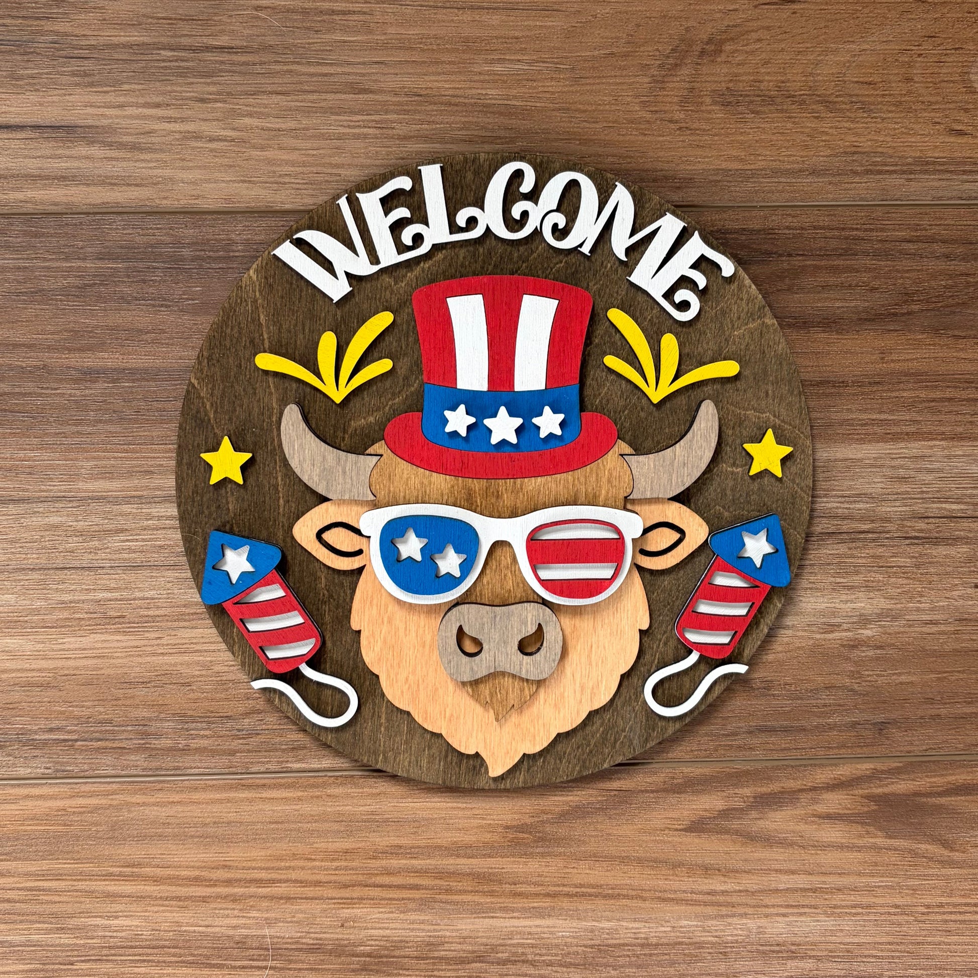 Decorative welcome sign with a bull wearing an American flag hat and sunglasses on a wooden background.