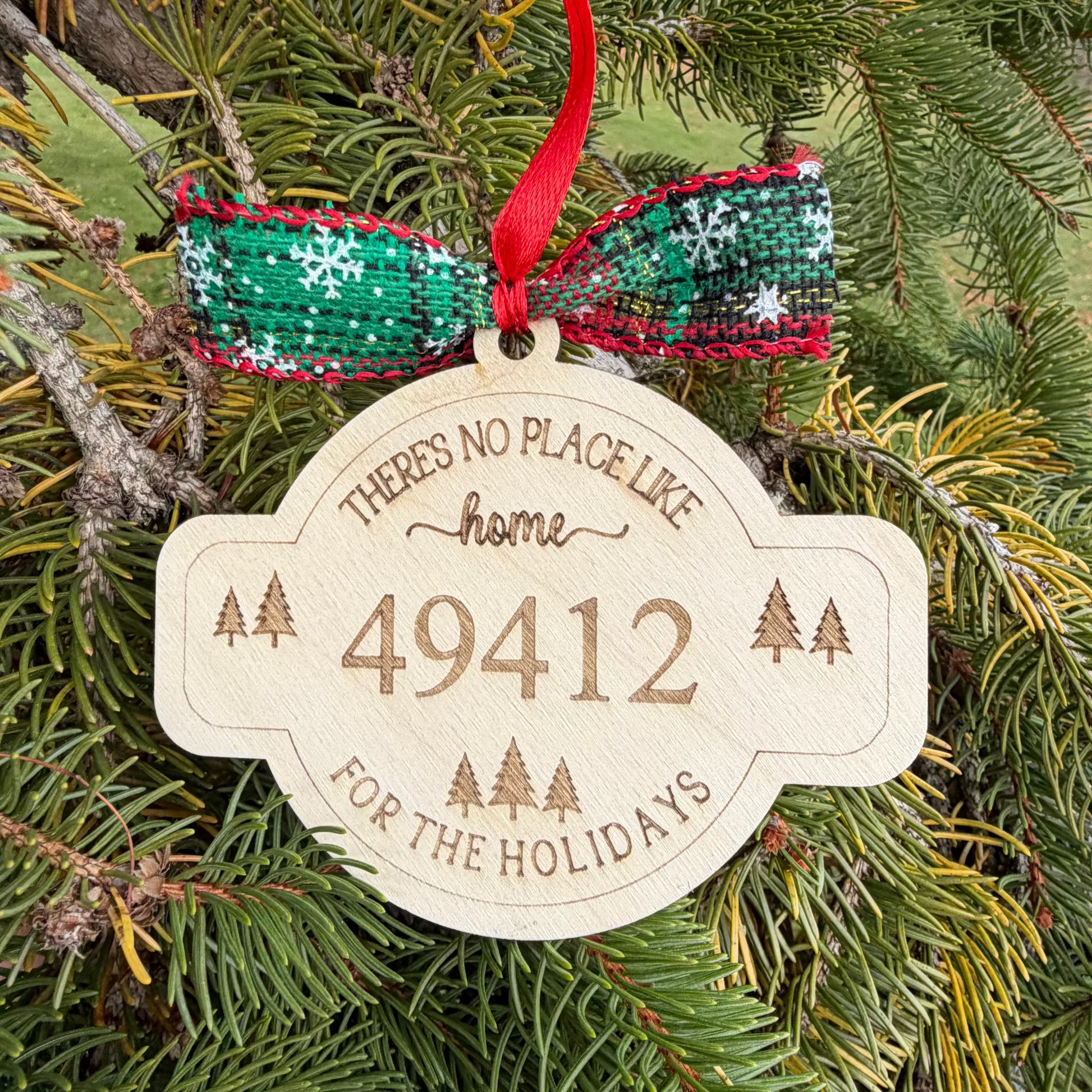 Decorative Christmas ornament with text and number on a green pine branch.