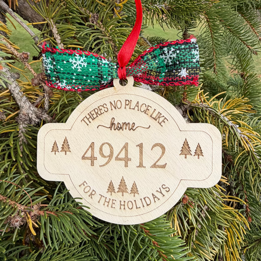 Decorative Christmas ornament with text and number on a green pine branch.